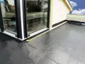 Gotowy balkon z hydroizolacją pod płytki. Czarna membrana zabezpiecza przed wilgocią, gotowa na wykończenie.