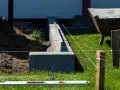 Budowa fundamentu pod ogrodzenie. Betonowe bloczki tworzą solidną podstawę, a niwelacyjna linka wyznacza precyzyjną linię.