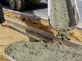Robotnicy wylewają świeży beton z samego piasku i cementu, tworząc nowy chodnik.