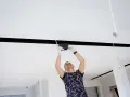 Montażysta instaluje oświetlenie LED w nowoczesnym suficie podwieszanym z wnęką.