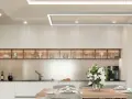 Nowoczesna kuchnia z drewnianą zabudową i białymi frontami. Sufit podwieszany, ile cm od sufitu, nie jest widoczny, ale jego obecność podkreśla elegancki charakter wnętrza.