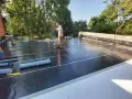 Pracownik wykonuje układanie płyt tarasowych na suchym betonie, używając palnika do obróbki papy.