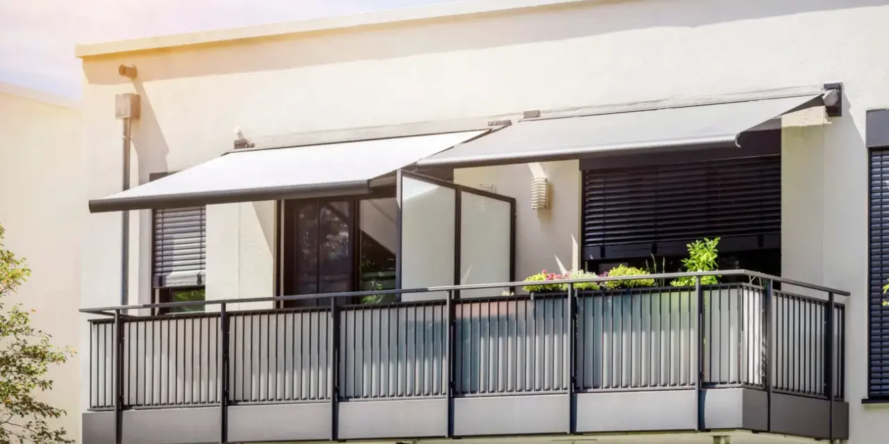 Nowoczesny balkon z balustradą i markizami. Szklana ścianka to pomysł, jak odgrodzić balkon, zapewniając prywatność i styl.
