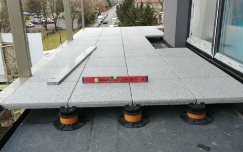 Układanie płyt na wspornikach tworzy wentylowany balkon. Poziomica zapewnia idealne dopasowanie.