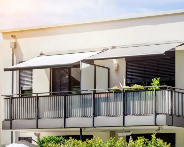 Nowoczesny balkon z balustradą i markizami. Szklana ścianka to pomysł, jak odgrodzić balkon, zapewniając prywatność i styl.
