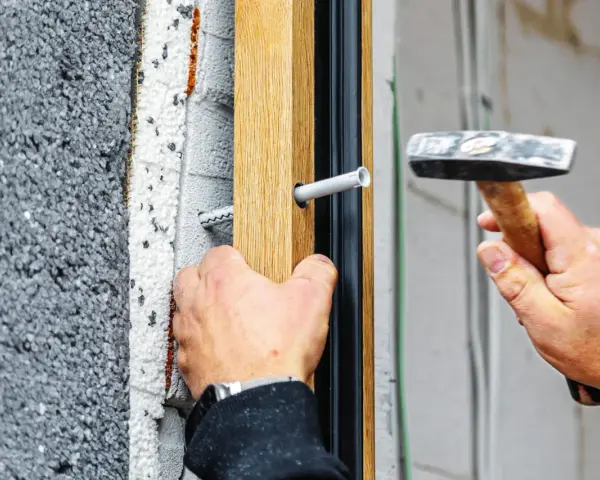 Montaż okna, wbijanie kołka rozporowego w drewnianą ramę. Właściwe kołki do karton-gipsu zapewnią stabilność.
