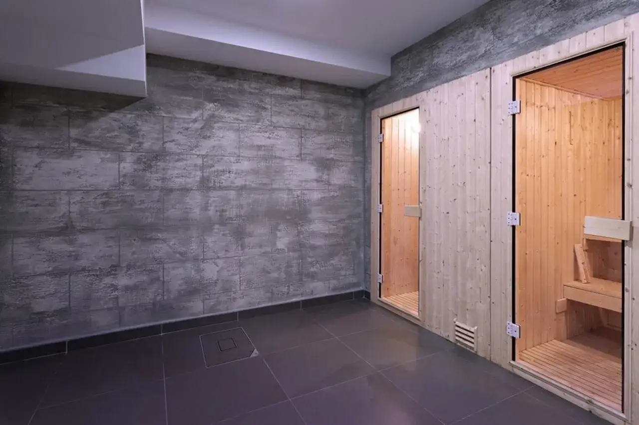 Nowoczesny pomysł na ściany w piwnicy: beton architektoniczny obok dwóch saun z drewna.